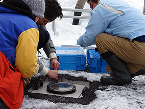 Researchers install a snow and ice monitoring sensor
